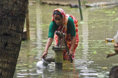 24 Temmuz 2020 'de Dhaka, Bangladeş yakınlarındaki Manikganj' daki evini su basınca bir kadın el pompasından temiz su topluyor. Güney Asya 'da şiddetli muson yağmurlarından kaynaklanan ölüm bilançosu yaklaşık 200' e yükseldi. Neredeyse dört milyon insan. 