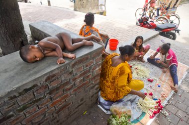 25 Temmuz 202 'de Bangladeş' in Dhaka kentindeki COVID-19 Coronavirüs salgınında evsiz bir aile çelenk üretiyor.