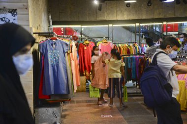 Bangladeşli müşteriler, 29 Temmuz 2020 'de Bangladeş' in Dhaka kentindeki COVID-19 Coronavirus salgını sırasında Kurban 'ın önündeki bir alışveriş merkezinden kıyafet almak için yüz maskesi takıyorlar.