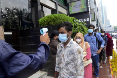 Bir güvenlik görevlisi 29 Temmuz 2020 'de Bangladeş' in Dhaka kentindeki COVID-19 Coronavirus salgını sırasında AVM 'nin önündeki alışveriş merkezinin girişindeki vücut ısısını kontrol ediyor.
