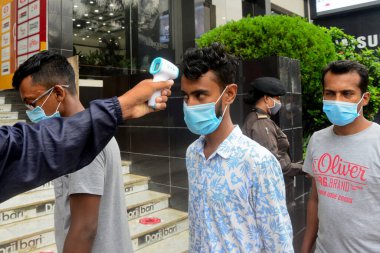 Bir güvenlik görevlisi 29 Temmuz 2020 'de Bangladeş' in Dhaka kentindeki COVID-19 Coronavirus salgını sırasında AVM 'nin önündeki alışveriş merkezinin girişindeki vücut ısısını kontrol ediyor.