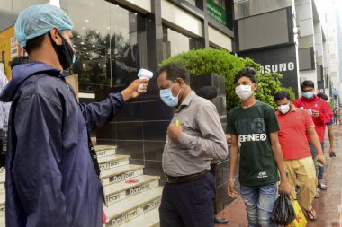 Bir güvenlik görevlisi 29 Temmuz 2020 'de Bangladeş' in Dhaka kentindeki COVID-19 Coronavirus salgını sırasında AVM 'nin önündeki alışveriş merkezinin girişindeki vücut ısısını kontrol ediyor.