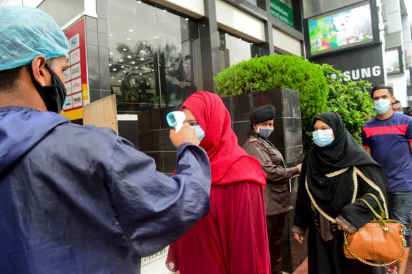 Bir güvenlik görevlisi 29 Temmuz 2020 'de Bangladeş' in Dhaka kentindeki COVID-19 Coronavirus salgını sırasında AVM 'nin önündeki alışveriş merkezinin girişindeki vücut ısısını kontrol ediyor.