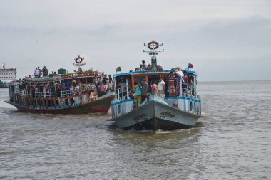 Yüz maskesi takan insanlar, 5 Ağustos 202 'de Bangladeş, Dhaka' da bayram bitiminden sonra başkente dönen Padma Nehri 'nde bir kalkış ile seyahat ediyorlar.