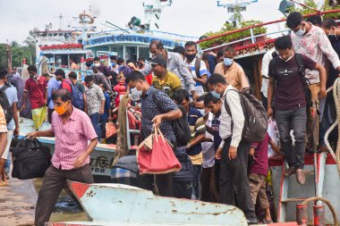 Yüz maskesi takan insanlar, 5 Ağustos 2020 'de Bangladeş' in Dhaka kentindeki Kurban Bayramı 'nın bitiminden sonra başkente döndüklerinde Padma Nehri' ndeki fırlatma istasyonuna varırlar.