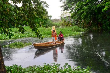 Vatandaşlar 6 Ağustos 2020 'de Bangladeş' in Dhaka şehrinin ovalarında sel sularından geçen bir tekneye biniyorlar.