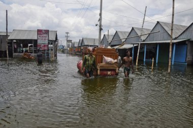7 Ağustos 2020 'de Dhaka, Bangladeş yakınlarındaki sel basmış caddelerden mobilyalarıyla geçen köylüler,