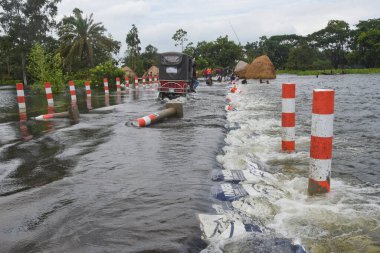 7 Ağustos 2020 'de Dhaka, Bangladeş yakınlarındaki sel basmış caddeden geçmeye çalışan yolcularla dolu bir araç görülüyor.