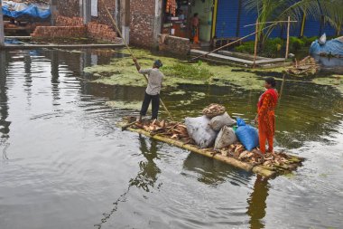 7 Ağustos 2020 'de Bangladeş, Dhaka yakınlarındaki Savar' daki sel sularında muz ağaçlarından yapılmış derme çatma bir sala binen köylü adam.