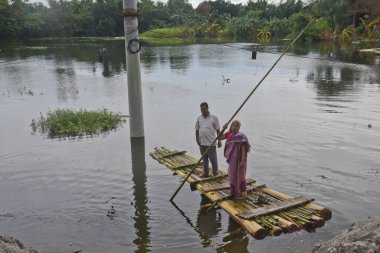 7 Ağustos 2020 'de Bangladeş, Dhaka yakınlarındaki Savar' daki sel sularında muz ağaçlarından yapılmış derme çatma bir sala binen köylü kadın görülüyor.