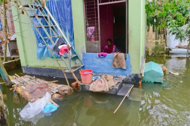 10 Ağustos 2020 'de Dhaka, Bangladeş yakınlarındaki Savar' da sel sularıyla çevrili olarak görülen köylü evinde oturuyor.