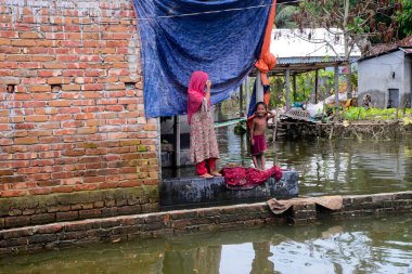 10 Ağustos 2020 'de Dhaka, Bangladeş yakınlarındaki Savar' da sel sularıyla çevrili köylü çocukları evlerinin önünde duruyor.