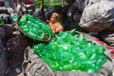 Kadın işçiler, 12 Ağustos 2020 'de Dhaka, Bangladeş' teki bir geri dönüşüm fabrikasında polietilen tereftalat (PET) şişelerini sınıflandırıyorlar. Plastik şişelerin geri dönüşümü son birkaç yılda büyüyen bir iş haline geldi. 