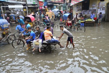 19 Haziran 2015 'te sağanak yağış neredeyse durgunluğa yol açtıktan sonra vatandaşlar, araçlar ve Rickshaw' lar Dhaka 'nın sel basmış sokaklarında yolcularla birlikte araba sürmeye çalıştı. Şiddetli muson yağmurlarının ardından Dhaka 'nın başkentinde bölgenin çoğu sular altında kaldı..