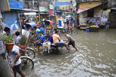 19 Haziran 2015 'te sağanak yağış neredeyse durgunluğa yol açtıktan sonra vatandaşlar, araçlar ve Rickshaw' lar Dhaka 'nın sel basmış sokaklarında yolcularla birlikte araba sürmeye çalıştı. Şiddetli muson yağmurlarının ardından Dhaka 'nın başkentinde bölgenin çoğu sular altında kaldı..