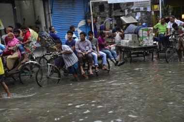 19 Haziran 2015 'te sağanak yağış neredeyse durgunluğa yol açtıktan sonra vatandaşlar, araçlar ve Rickshaw' lar Dhaka 'nın sel basmış sokaklarında yolcularla birlikte araba sürmeye çalıştı. Şiddetli muson yağmurlarının ardından Dhaka 'nın başkentinde bölgenin çoğu sular altında kaldı..