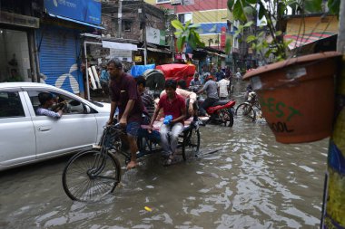 19 Haziran 2015 'te sağanak yağış neredeyse durgunluğa yol açtıktan sonra vatandaşlar, araçlar ve Rickshaw' lar Dhaka 'nın sel basmış sokaklarında yolcularla birlikte araba sürmeye çalıştı. Şiddetli muson yağmurlarının ardından Dhaka 'nın başkentinde bölgenin çoğu sular altında kaldı..
