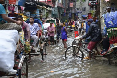 19 Haziran 2015 'te sağanak yağış neredeyse durgunluğa yol açtıktan sonra vatandaşlar, araçlar ve Rickshaw' lar Dhaka 'nın sel basmış sokaklarında yolcularla birlikte araba sürmeye çalıştı. Şiddetli muson yağmurlarının ardından Dhaka 'nın başkentinde bölgenin çoğu sular altında kaldı..