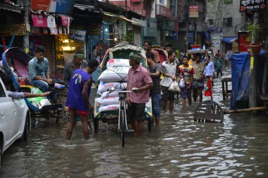 19 Haziran 2015 'te sağanak yağış neredeyse durgunluğa yol açtıktan sonra vatandaşlar, araçlar ve Rickshaw' lar Dhaka 'nın sel basmış sokaklarında yolcularla birlikte araba sürmeye çalıştı. Şiddetli muson yağmurlarının ardından Dhaka 'nın başkentinde bölgenin çoğu sular altında kaldı..