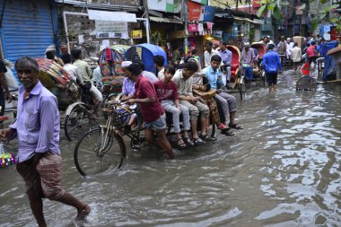 19 Haziran 2015 'te sağanak yağış neredeyse durgunluğa yol açtıktan sonra vatandaşlar, araçlar ve Rickshaw' lar Dhaka 'nın sel basmış sokaklarında yolcularla birlikte araba sürmeye çalıştı. Şiddetli muson yağmurlarının ardından Dhaka 'nın başkentinde bölgenin çoğu sular altında kaldı..
