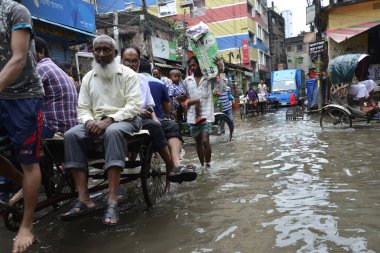 19 Haziran 2015 'te sağanak yağış neredeyse durgunluğa yol açtıktan sonra vatandaşlar, araçlar ve Rickshaw' lar Dhaka 'nın sel basmış sokaklarında yolcularla birlikte araba sürmeye çalıştı. Şiddetli muson yağmurlarının ardından Dhaka 'nın başkentinde bölgenin çoğu sular altında kaldı..