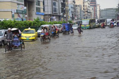 Vatandaşlar, araçlar ve Rickshaw 'lar, 05 Temmuz 2017' de sağanak yağış neredeyse duraksadıktan sonra Dhaka şehrinin sel basmış sokaklarında yolcularla birlikte araba sürmeye çalışırlar. Şiddetli muson yağmurlarının ardından B bölgesinin başkenti Dhaka 'da sel baskınına neden oldu.