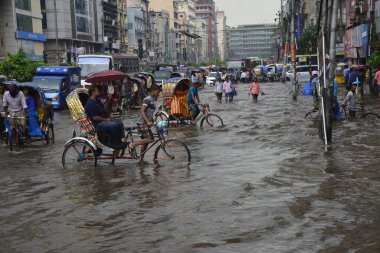 Vatandaşlar, araçlar ve Rickshaw 'lar, 05 Temmuz 2017' de sağanak yağış neredeyse duraksadıktan sonra Dhaka şehrinin sel basmış sokaklarında yolcularla birlikte araba sürmeye çalışırlar. Şiddetli muson yağmurlarının ardından B bölgesinin başkenti Dhaka 'da sel baskınına neden oldu.