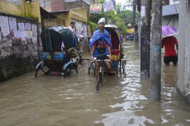 26 Temmuz 2017 'de sağanak yağış neredeyse durgunluğa yol açtıktan sonra, vatandaşlar Dhaka' nın sel basmış sokaklarında yürüyor. Şiddetli muson yağmurlarının ardından Bangladeş 'in başkenti Dhaka' nın büyük bölümü sular altında kaldı.. 