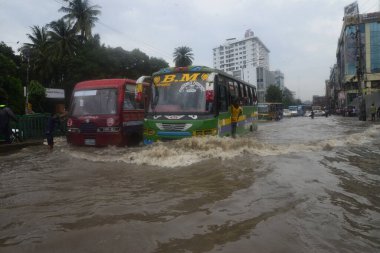 26 Temmuz 2017 'de sağanak yağış neredeyse durgunluğa yol açtıktan sonra, vatandaşlar Dhaka' nın sel basmış sokaklarında yürüyor. Şiddetli muson yağmurlarının ardından Bangladeş 'in başkenti Dhaka' nın büyük bölümü sular altında kaldı.. 