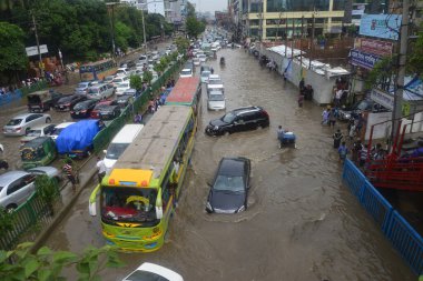 26 Temmuz 2017 'de sağanak yağış neredeyse durgunluğa yol açtıktan sonra, vatandaşlar Dhaka' nın sel basmış sokaklarında yürüyor. Şiddetli muson yağmurlarının ardından Bangladeş 'in başkenti Dhaka' nın büyük bölümü sular altında kaldı.. 