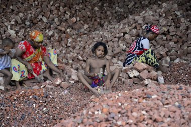 Bangladeşli kadınlar ve çocuklar 13 Mayıs 2017 'de Dhaka, Bangladeş' teki Demra tuğla kırma sahasında tuğla kırarlar. Nüfusun yarısından fazlası yoksulluk sınırının altında yaşadığı için, kadınlar ve çocuklar çoğunlukla tuğla gibi ağır işçiliğe zorlanıyorlar.