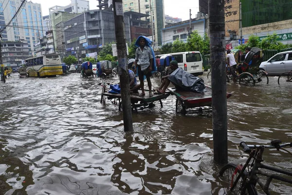 Vatandaşlar, araçlar ve Rickshaw 'lar, 05 Temmuz 2017' de sağanak yağış neredeyse duraksadıktan sonra Dhaka şehrinin sel basmış sokaklarında yolcularla birlikte araba sürmeye çalışırlar. Şiddetli muson yağmurlarının ardından B bölgesinin başkenti Dhaka 'da sel baskınına neden oldu.