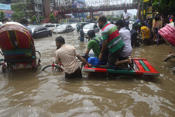Citizens are walking through the flooded streets of Dhaka after heavy rainfalls caused almost-standstill, on July 26, 2017. After heavy monsoon rains caused flooded most of area in the capital of Dhaka in Bangladesh. 