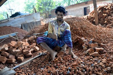 Bangladeşli bir adam 13 Mayıs 2017 'de Dhaka, Bangladeş' teki Demra tuğla kırma sahasında tuğla kırıyor. Nüfusun yarısından fazlası yoksulluk sınırının altında yaşadığı için, kadınlar ve çocuklar sık sık tuğla kırmak gibi ağır işçiliğe zorlanıyorlar. Kablo