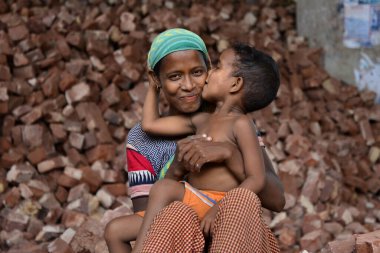 İşçi bir anne, Bangladeş 'te, Dhaka' da çocuklarının iş yerinde öpüşürken eğleniyor. 13 Mayıs 2017