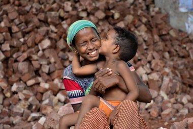 İşçi bir anne, Bangladeş 'te, Dhaka' da çocuklarının iş yerinde öpüşürken eğleniyor. 13 Mayıs 2017