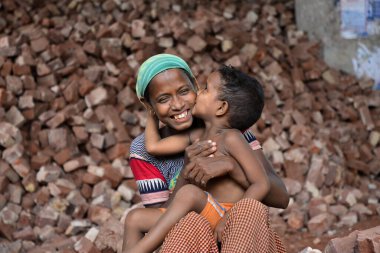 İşçi bir anne, Bangladeş 'te, Dhaka' da çocuklarının iş yerinde öpüşürken eğleniyor. 13 Mayıs 2017