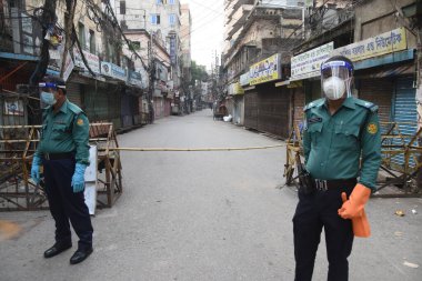 7 Mayıs 2020 'de Bangladeş' in Dhaka kentindeki COVID-19 koronavirüsüne karşı önleyici tedbir olarak hükümet tarafından ülke çapında uygulanan tecrit sırasında polis personeli engelli bir bölgenin girişinde nöbet tutuyor..