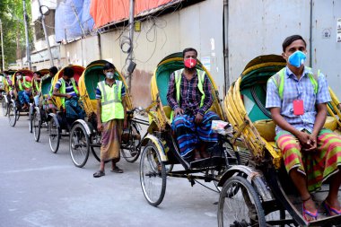 Bangladeş Rickshaw sürücüleri, 27 Mart 2020 tarihinde Bangladeş 'in Dhaka kentindeki COVID-19 koronavirüsüne karşı önleyici bir tedbir olarak hükümet tarafından uygulanan tecrit sırasında yolcuları bekliyor.