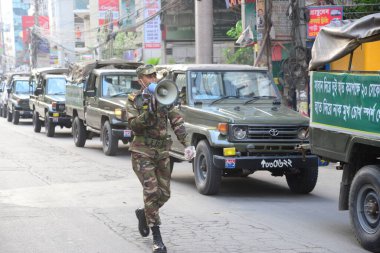 Bangladeş Ordusu askerleri, 3 Nisan 2020 'de Bangladeş' in Dhaka kentindeki COVID-19 Coronavirüs salgınına karşı önleyici bir önlem olarak ülke çapında tecrit sırasında sokaklarda devriye gezen halkın evlerinde kaldığının farkında.. 