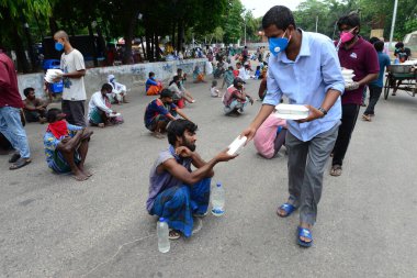 Bangladeş, Dhaka 'daki Dhaka Üniversitesi Kampüsü bölgesinde 3 Haziran 2020' de meydana gelen koronavirüs salgını sırasında evsizler arasında gıda dağıtımı yapan Dhaka Üniversitesi öğrencileri. 