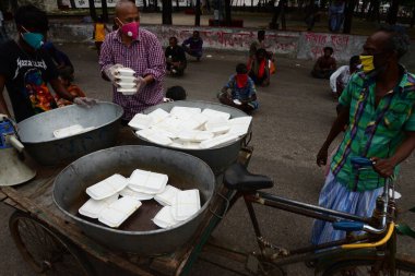 Bangladeş, Dhaka 'daki Dhaka Üniversitesi Kampüsü bölgesinde 3 Haziran 2020' de meydana gelen koronavirüs salgını sırasında evsizler arasında gıda dağıtımı yapan Dhaka Üniversitesi öğrencileri. 