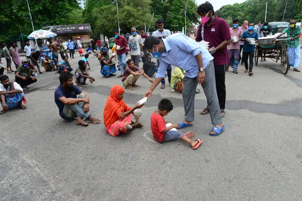 Bangladeş, Dhaka 'daki Dhaka Üniversitesi Kampüsü bölgesinde 3 Haziran 2020' de meydana gelen koronavirüs salgını sırasında evsizler arasında gıda dağıtımı yapan Dhaka Üniversitesi öğrencileri. 