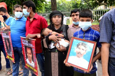 Akrabalar, 29 Ağustos 2020 'de Bangladeş' in Dhaka kentindeki Shahbagh bölgesinde, Uluslararası Kaybolma Günü öncesinde kayıp aile üyelerinin portrelerini tutuyor. İnsan zinciri mitingi Mayer Daak platformu tarafından düzenlenir.