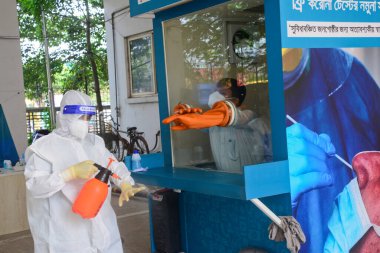 Sağlık çalışanı, 29 Ağustos 2020 'de Bangladeş' in Dhaka kentindeki koronavirüs salgınının ortasında Mugda Tıp Fakültesi ve Hastanesi 'nde yaşayan bir hastadan burun çubuğu örneği aldıktan sonra dezenfektan püskürtüyor.