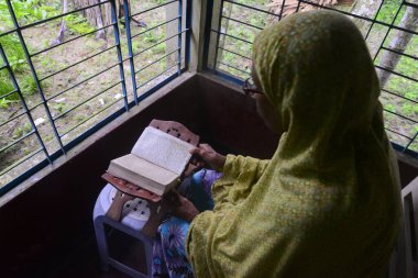 1 Ekim 2020 'de Jamalpur İlçesi, Bangladeş' teki evinde Müslüman bir kadın Al Kur 'an okur.