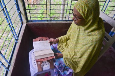 1 Ekim 2020 'de Jamalpur İlçesi, Bangladeş' teki evinde Müslüman bir kadın Al Kur 'an okur.