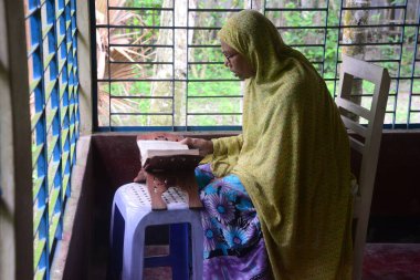 1 Ekim 2020 'de Jamalpur İlçesi, Bangladeş' teki evinde Müslüman bir kadın Al Kur 'an okur.