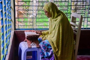 1 Ekim 2020 'de Jamalpur İlçesi, Bangladeş' teki evinde Müslüman bir kadın Al Kur 'an okur.