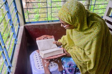 1 Ekim 2020 'de Jamalpur İlçesi, Bangladeş' teki evinde Müslüman bir kadın Al Kur 'an okur.